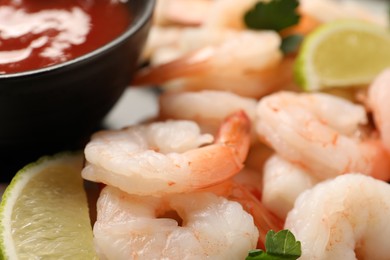 Photo of Tasty boiled shrimps with cocktail sauce, parsley and lime on plate, closeup