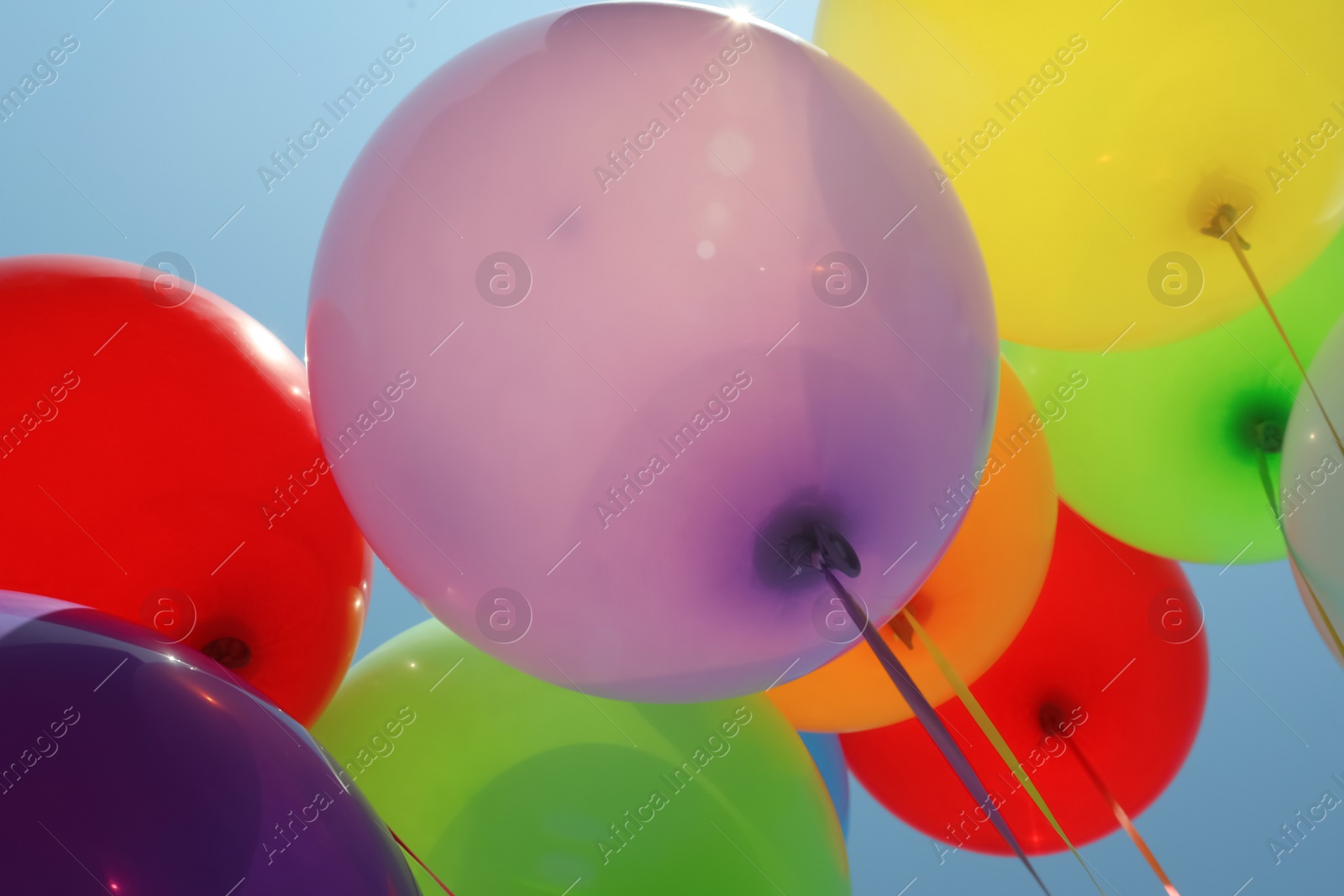 Photo of Bunch of colorful balloons against blue sky, low angle view