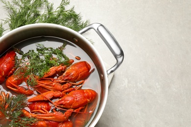 Photo of Fresh delicious crayfishes in pot on light grey table, flat lay. Space for text
