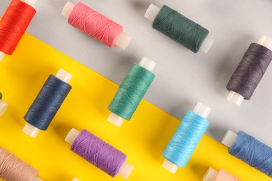 Photo of Different sewing threads on color background, flat lay