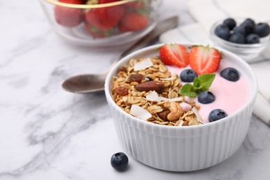 Photo of Tasty granola, yogurt and fresh berries in bowl on white marble table, closeup with space for text. Healthy breakfast