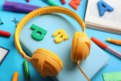 Photo of Books, headphones and stationery on light blue background, closeup
