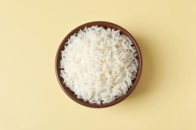 Bowl of tasty cooked rice on color background, top view