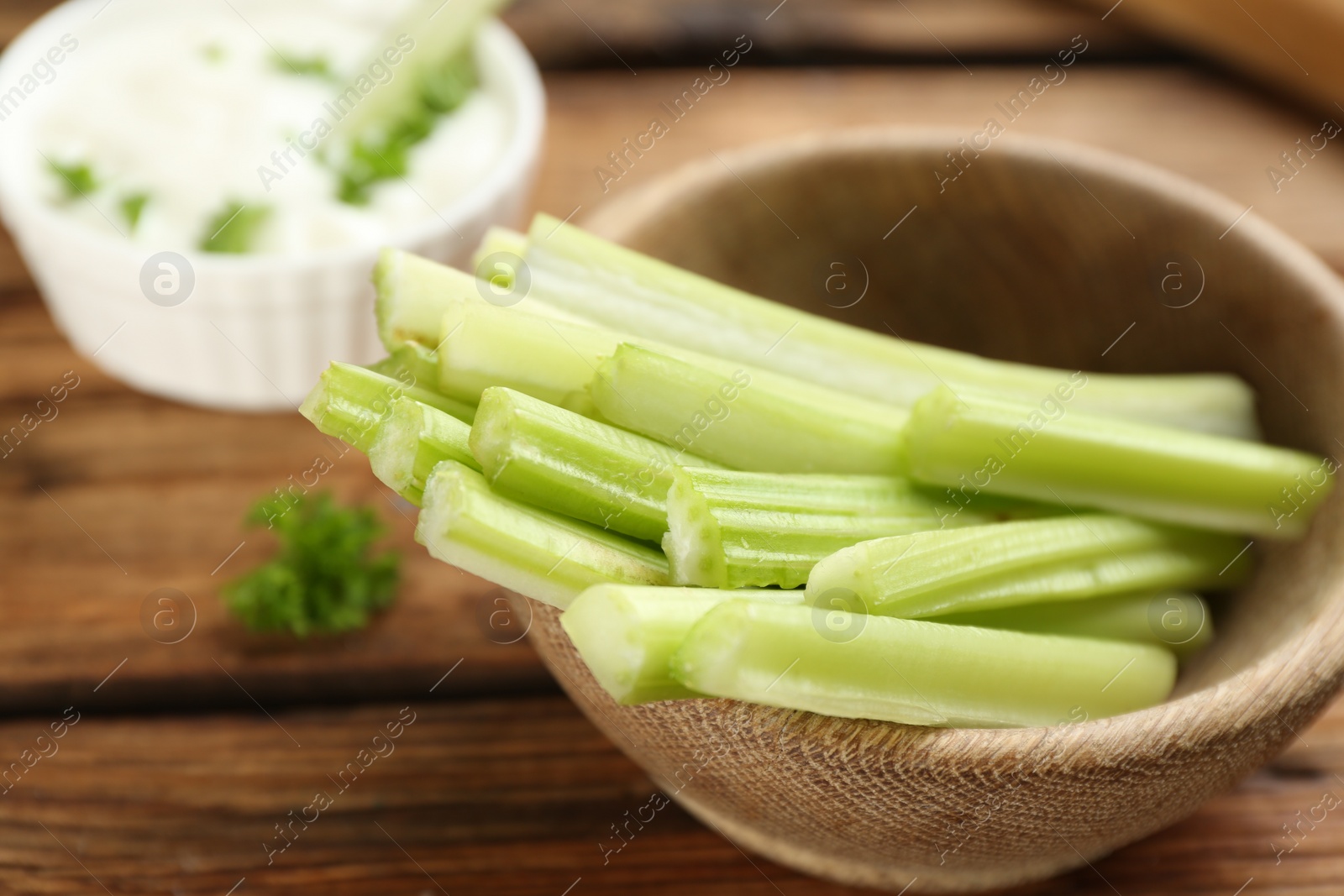 Photo of Celery sticks in wooden bowl on table, closeup