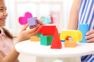 Woman and her child playing with colorful blocks at home, closeup