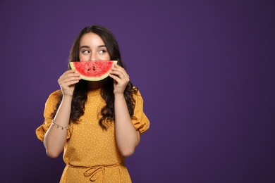 Beautiful young woman with watermelon on purple background. Space for text