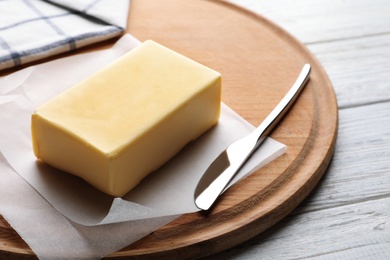 Photo of Wooden board with fresh butter and knife on table