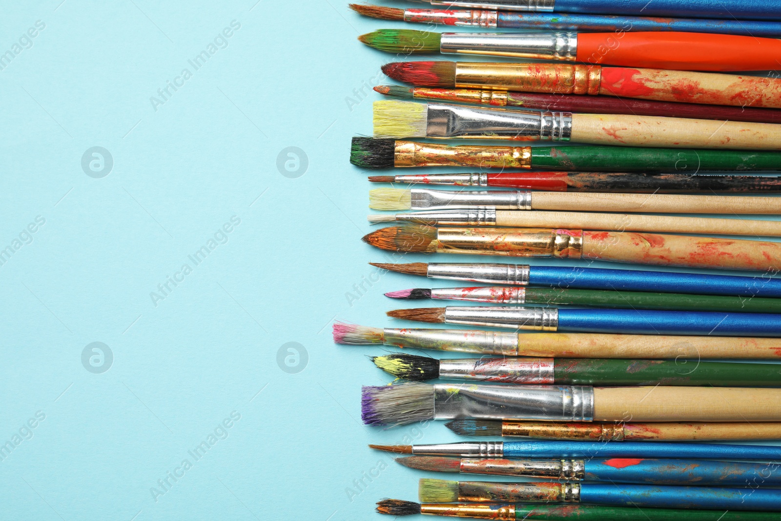 Photo of Different paint brushes on color background, top view with space for text