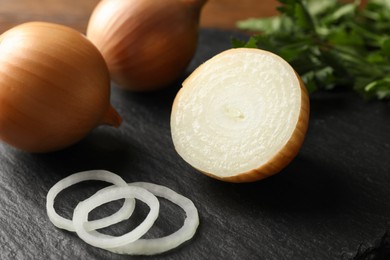 Whole and cut onions on black table, closeup