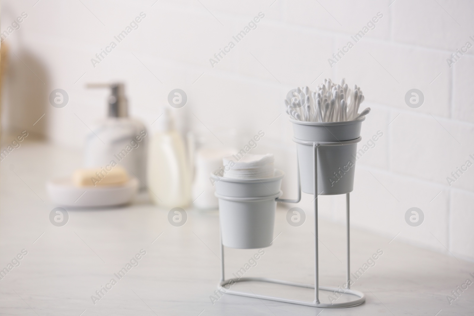 Photo of Cotton buds and pads on white table in bathroom, space for text