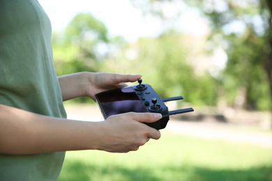 Photo of Woman holding new modern drone controller outdoors, closeup of hands