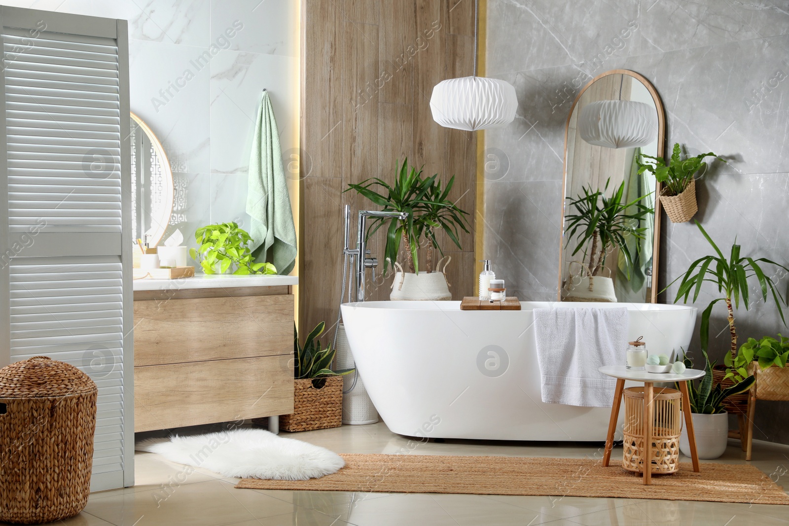 Photo of Modern white tub and beautiful green houseplants in bathroom. Interior design