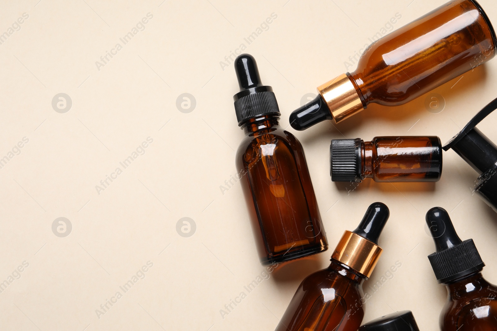 Photo of Many bottles with face serums on beige background, flat lay. Space for text