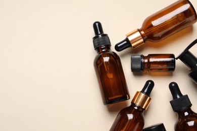 Photo of Many bottles with face serums on beige background, flat lay. Space for text