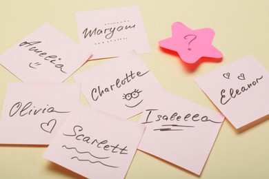 Photo of Choosing baby name. Paper stickers with different names and question mark on beige background