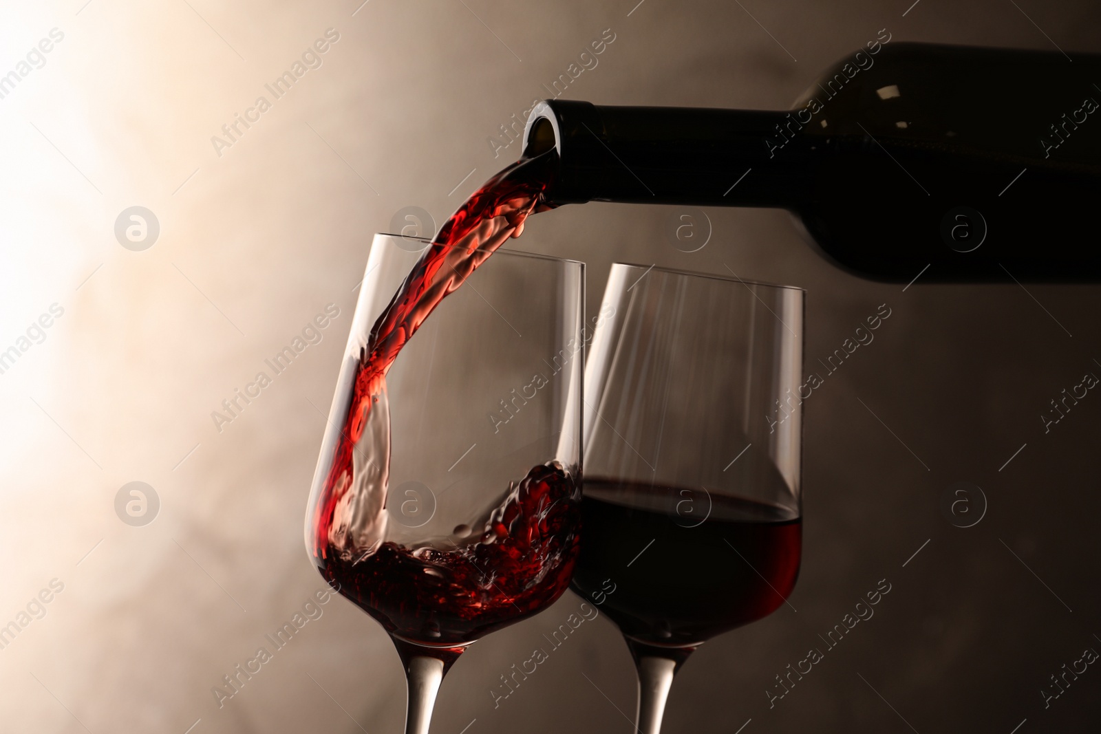 Photo of Pouring wine from bottle into glass on color background