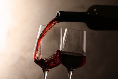 Pouring wine from bottle into glass on color background