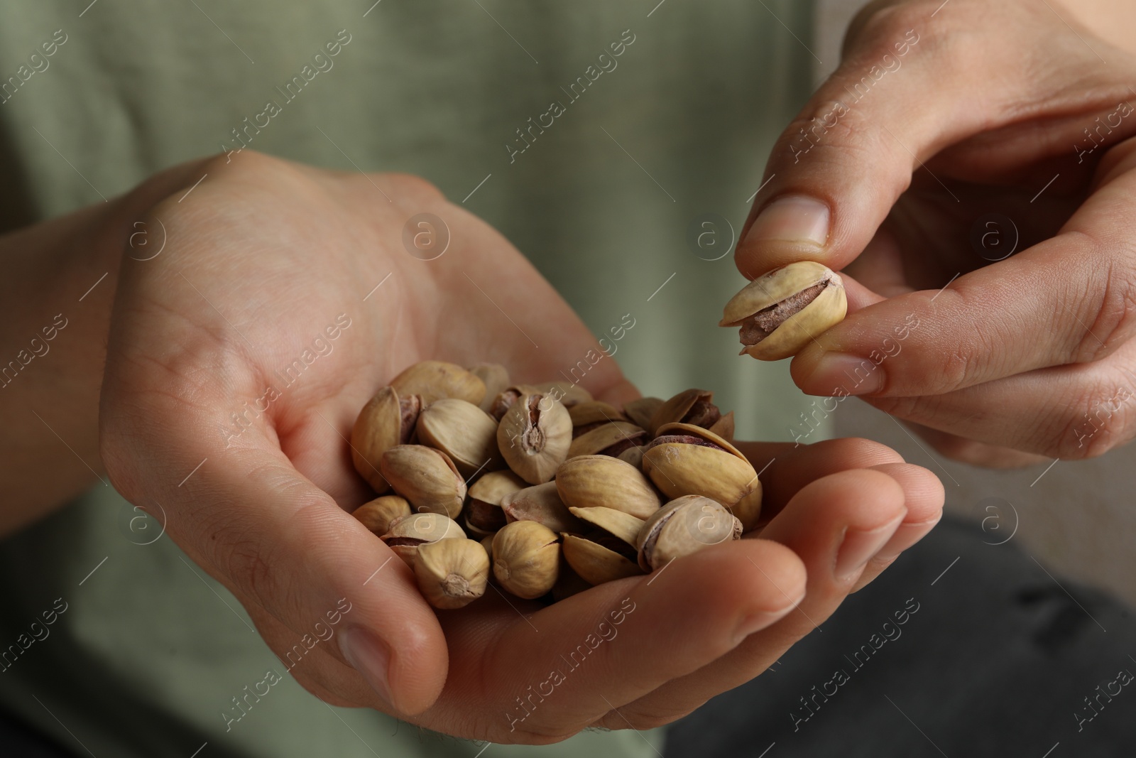 Photo of Woman holding tasty roasted pistachio nuts, closeup