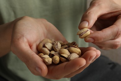 Photo of Woman holding tasty roasted pistachio nuts, closeup