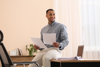 Photo of Happy man working with documents on wooden table in office