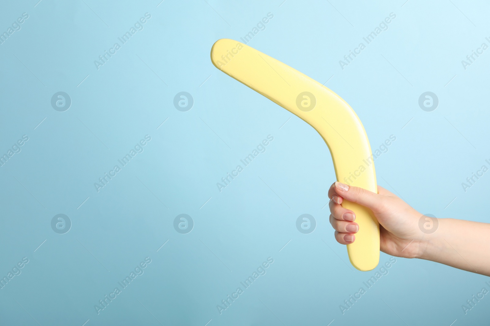 Photo of Woman holding boomerang on light blue background, closeup. Space for text