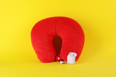 Photo of Red travel pillow and earphones on yellow background