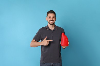 Photo of Man pointing at red container of motor oil on light blue background