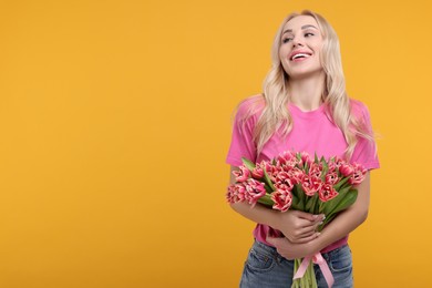 Happy young woman with beautiful bouquet on orange background. Space for text