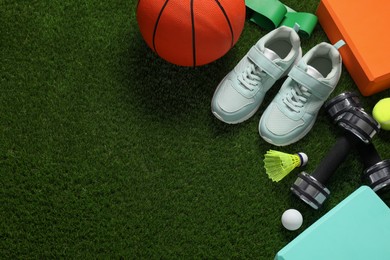 Photo of Different sport tools on green grass, flat lay. Space for text