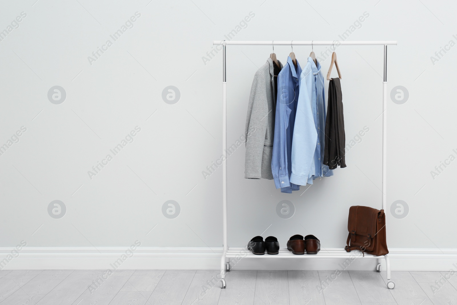 Photo of Rack with stylish men's clothes in room. Space for text