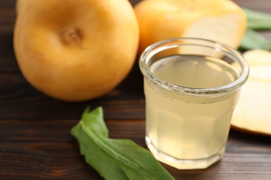 Photo of Glass of fresh natural turnip juice, cut and whole roots on wooden table, closeup. Space for text