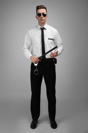 Photo of Male security guard with police baton on color background