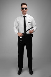 Male security guard with police baton on color background