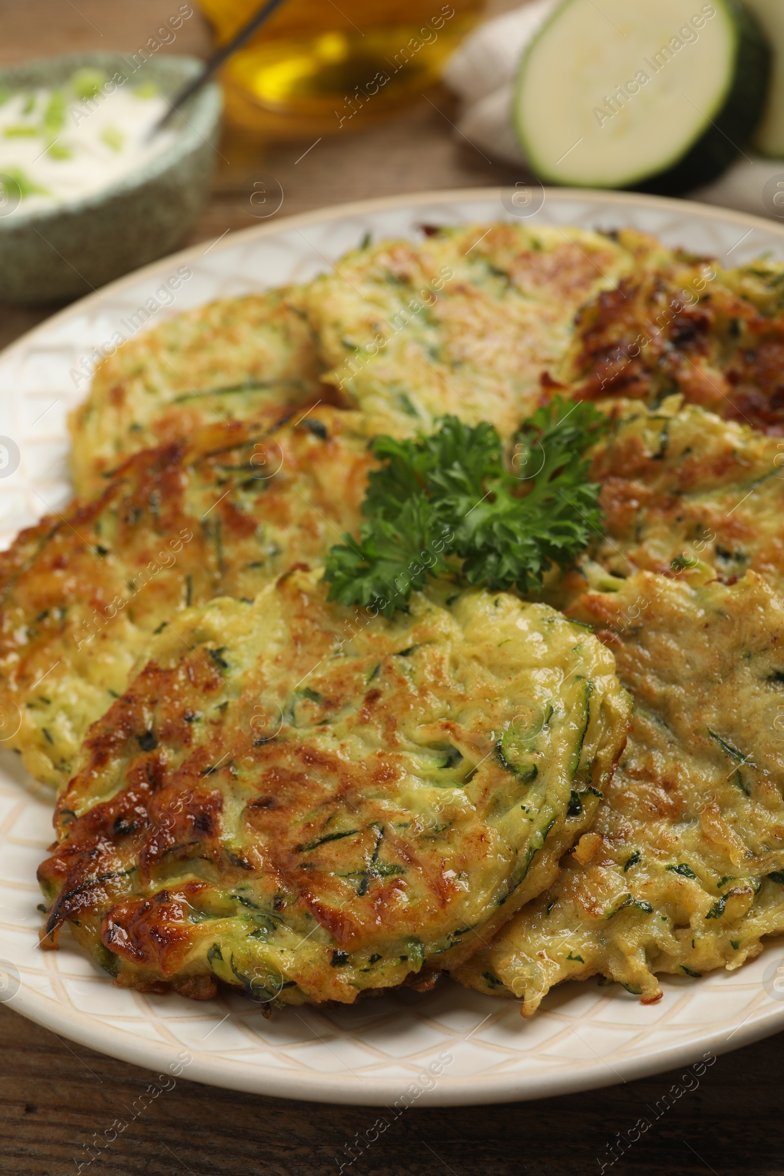 Photo of Delicious zucchini fritters served on wooden table, closeup