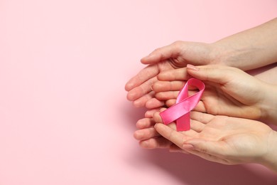 Breast cancer awareness. Women holding pink ribbon on color background, top view. Space for text