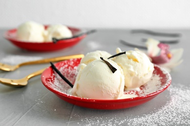 Photo of Plate with tasty vanilla ice cream on grey table