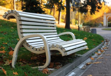 Photo of White wooden bench in park on sunny day