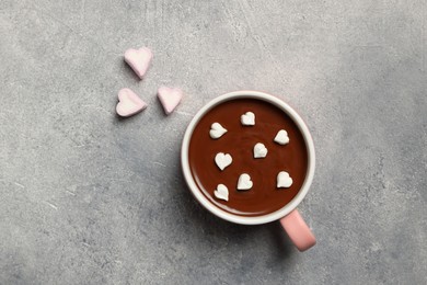 Cup of hot chocolate with heart shaped marshmallows on light grey table, flat lay