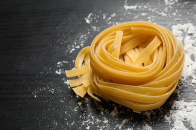 Photo of Tagliatelle pasta on grey wooden table, closeup