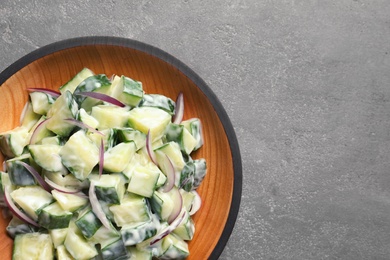 Photo of Wooden dish with fresh creamy cucumber salad on table, top view. Space for text