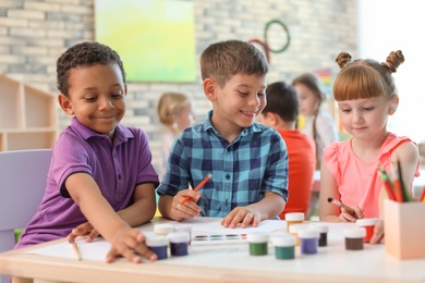 Photo of Cute little children painting at table indoors. Learning by playing