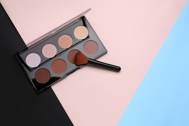 Photo of Contouring palette and brush on color background, flat lay with space for text. Professional cosmetic product