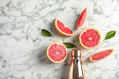 Flat lay composition with grapefruits, bottle of juice and space for text on marble background