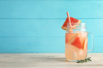 Photo of Mason jar with grapefruit cocktail on table. Space for text