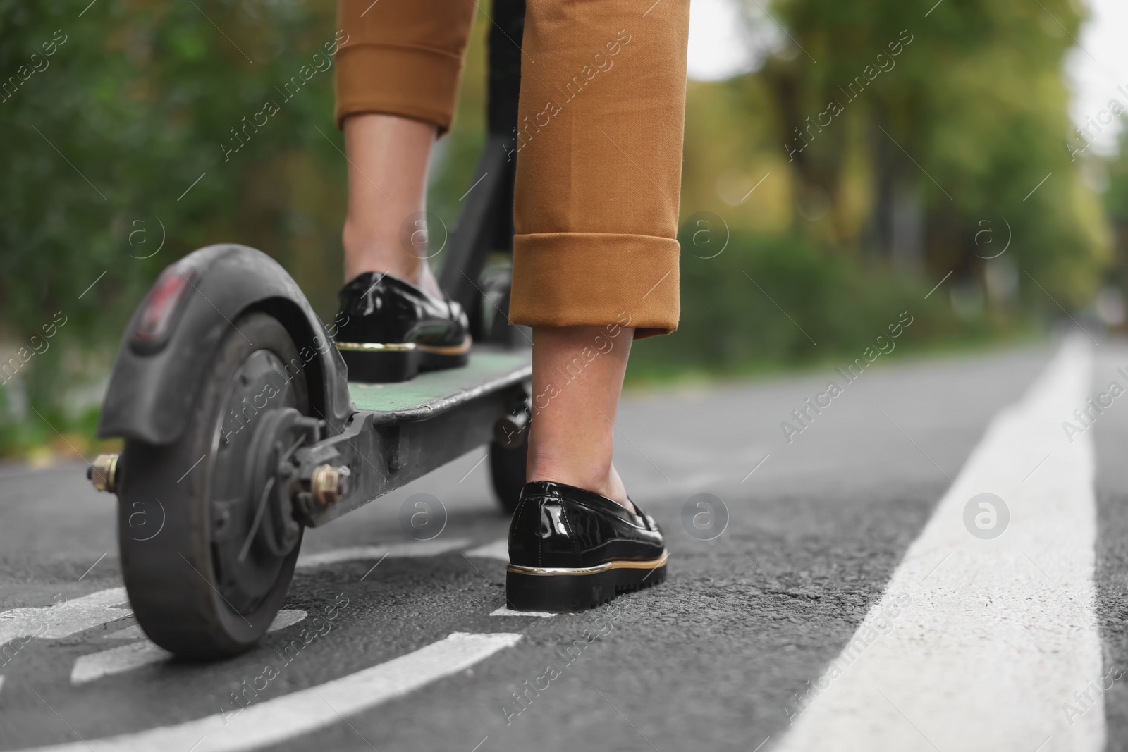 Photo of Businesswoman with modern electric kick scooter on city street, closeup. Space for text