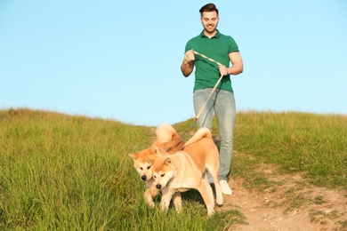 Photo of Young man walking his adorable Akita Inu dogs outdoors