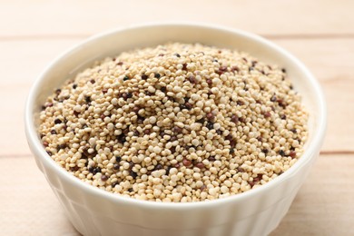 Photo of Raw quinoa seeds in bowl on table, closeup