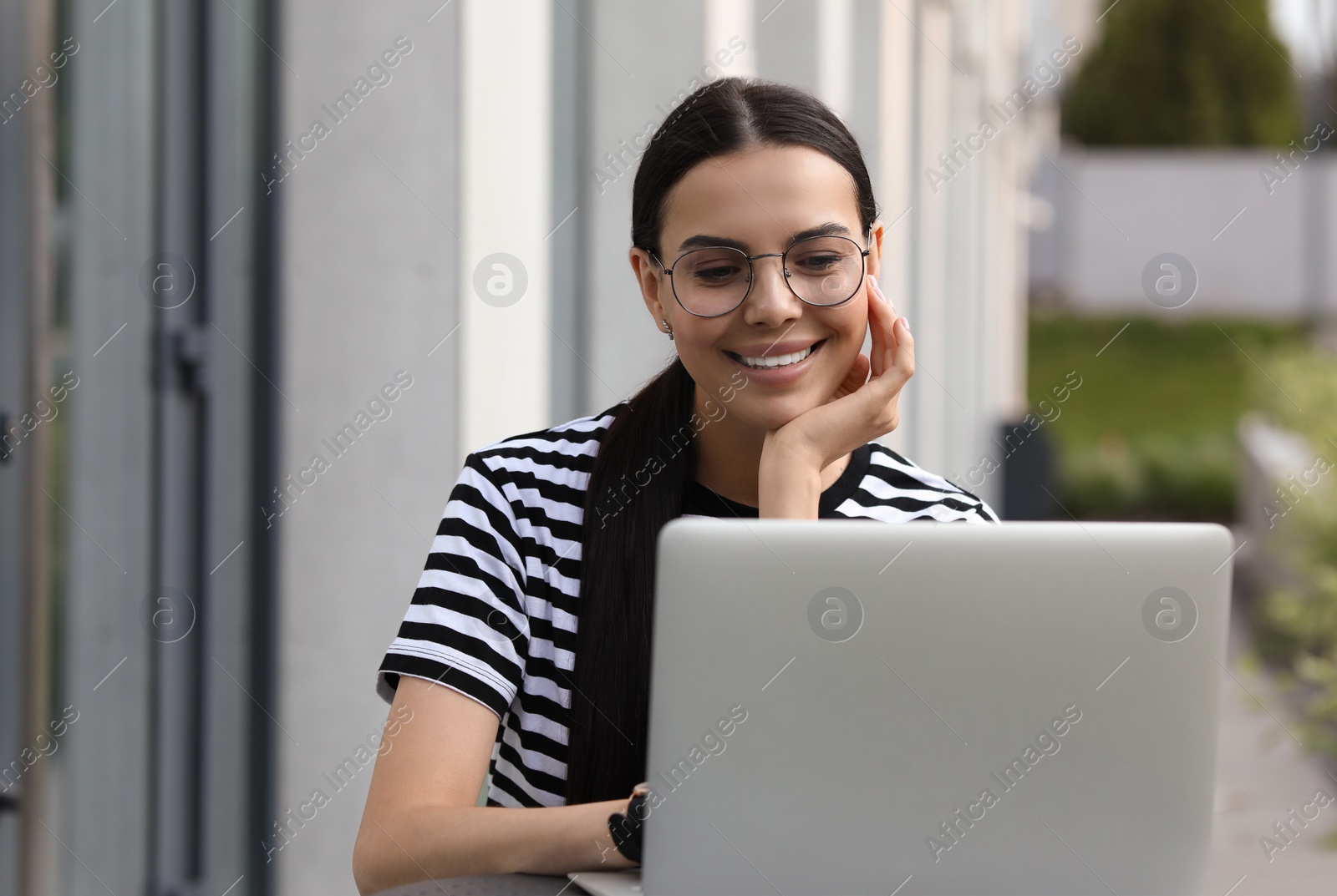 Photo of Happy young woman using modern laptop outdoors