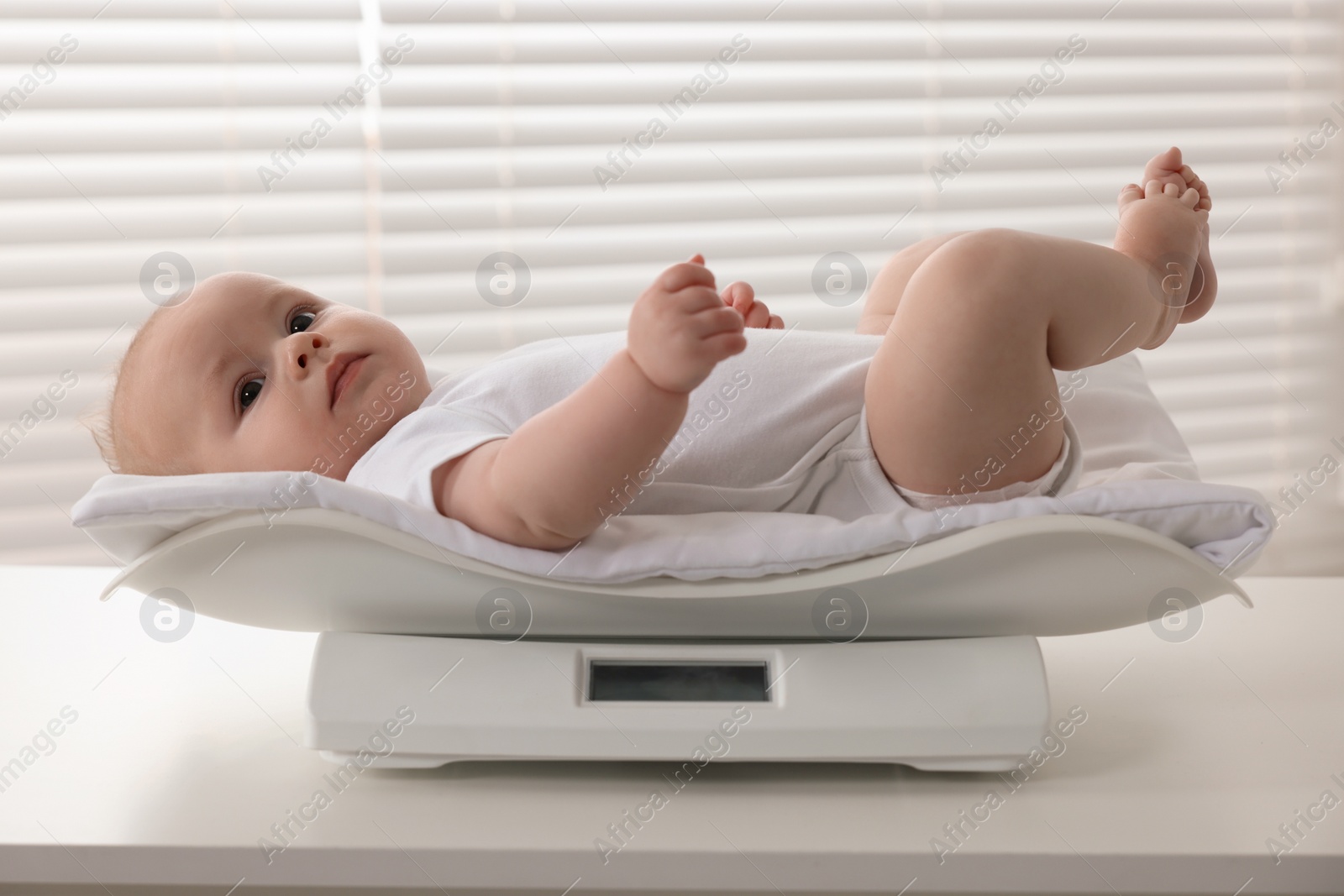 Photo of Cute little baby lying on scales in clinic