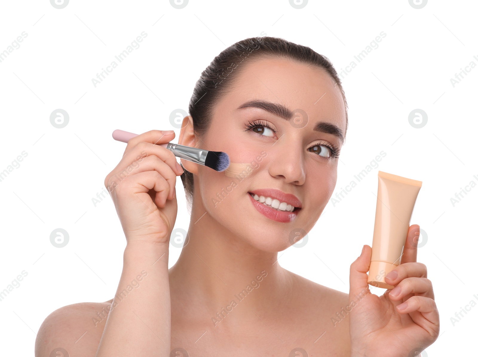 Photo of Woman with tube applying foundation on face using brush against white background